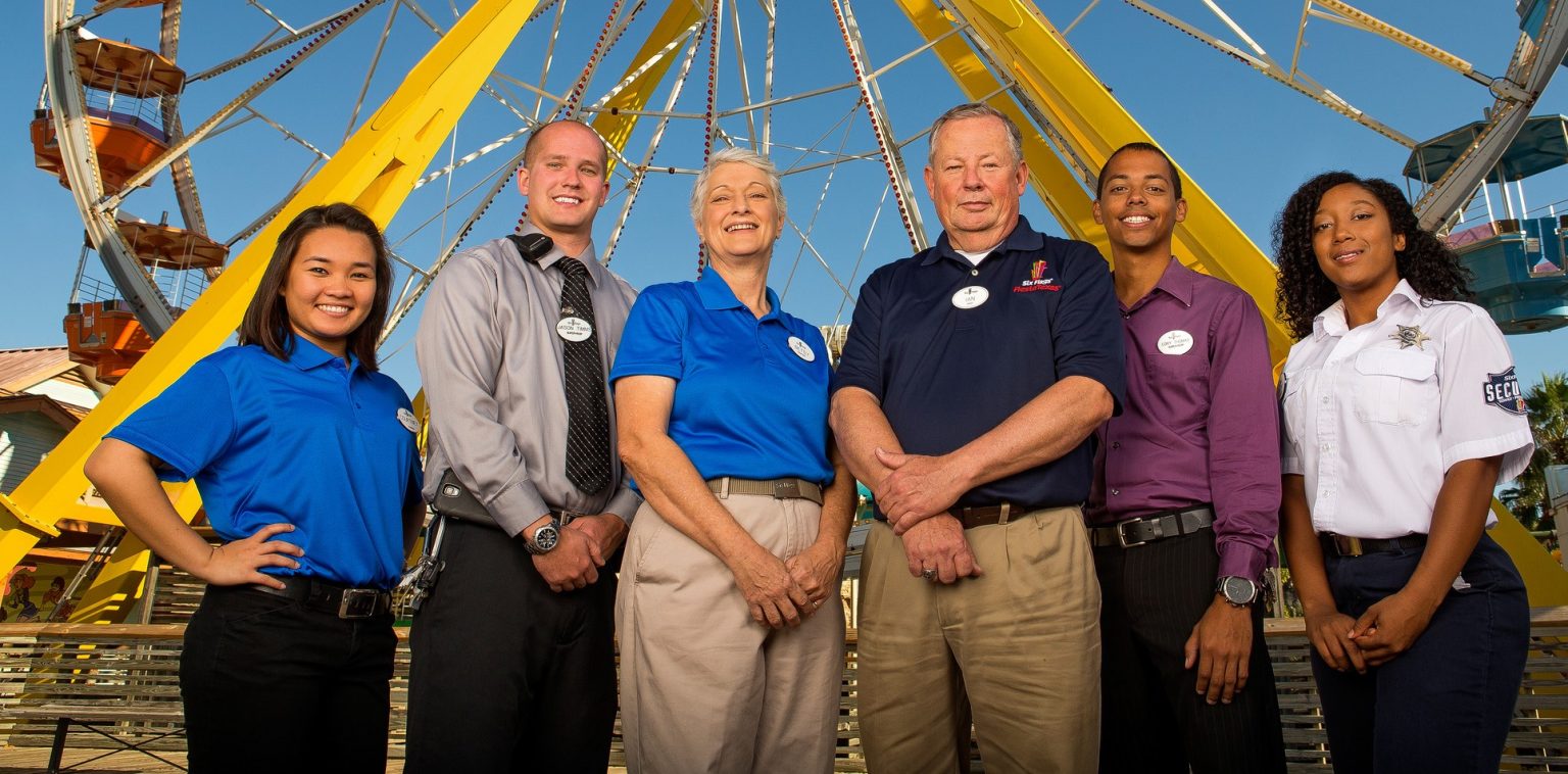 Six Flags staff standing in front of a Ferris Wheel.
