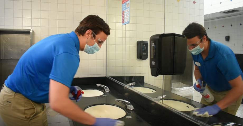 a masked employee sanitizing a bathroom at six Flags